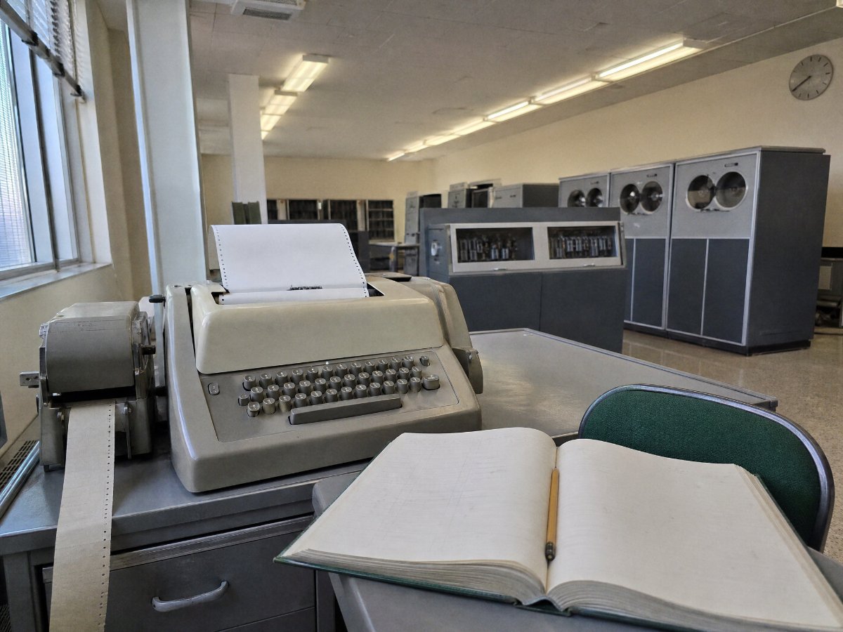 1960s computer room with teletype and log book